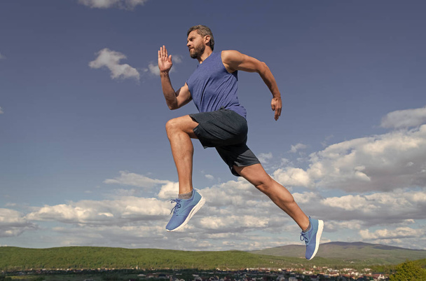 energický muž sportovec s svalnatým tělem běh ve sportovním oblečení venku na obloze pozadí, jogging - Fotografie, Obrázek