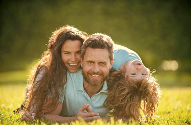 Anne babanın ve oğlunun mutlu ailesi yaz parkında yeşil çimlerde, ailede rahatlar. - Fotoğraf, Görsel