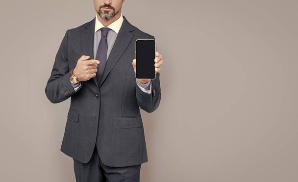 luottavainen liikemies puku osoittaa matkapuhelin, kopioi tilaa, moderni gadget. - Valokuva, kuva