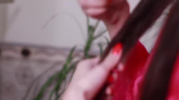 affascinante donna bruna spazzolando i suoi lunghi capelli sani in vestaglia femminile rosa. routine mattutina. cura dei capelli a casa. - Filmati, video