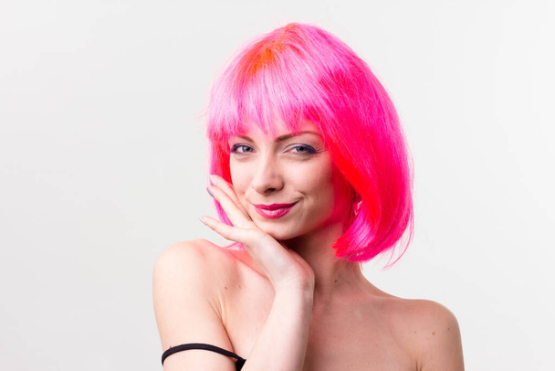 Imagen de la hermosa mujer excitada en la peluca riendo mientras posando con dulces aislados sobre fondo rosa
 - Foto, Imagen