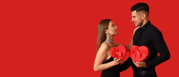 Happy young couple with gifts on red background. Banner for Valentine's Day  - 写真・画像