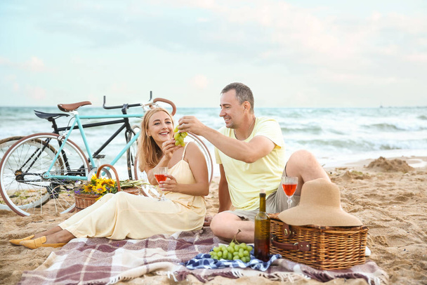 Mature couple having picnic near sea on summer day - Zdjęcie, obraz
