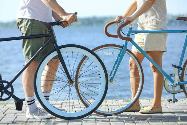 Coppia matura con biciclette passeggiando lungo la riva del fiume il giorno d'estate - Foto, immagini