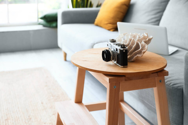 Wooden step ladder with photo camera near sofa in interior of living room - 写真・画像
