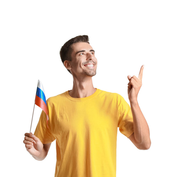 Jeune homme heureux avec le drapeau national de la Russie montrant quelque chose sur fond blanc - Photo, image