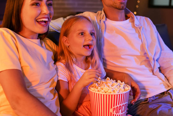 Szczęśliwa rodzina z popcornem ogląda wieczorem film w domu - Zdjęcie, obraz