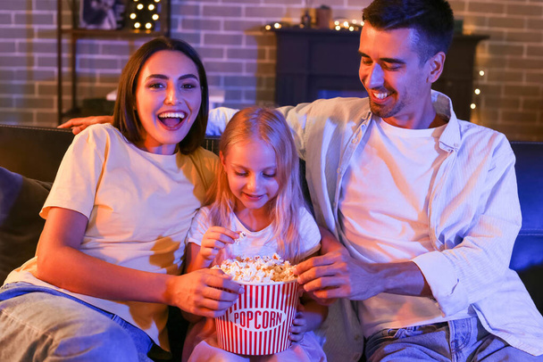 Happy family with popcorn watching movie at home in evening - Foto, Imagen