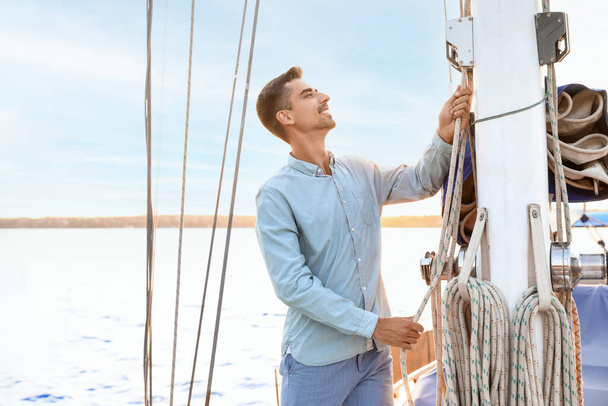 Young man adjusting the rigging of his yacht - Foto, Bild