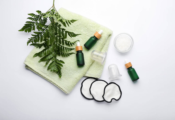Composição com garrafas de óleo essencial, sal marinho, toalha e frascos de vácuo para massagem anti-celulite sobre fundo branco - Foto, Imagem