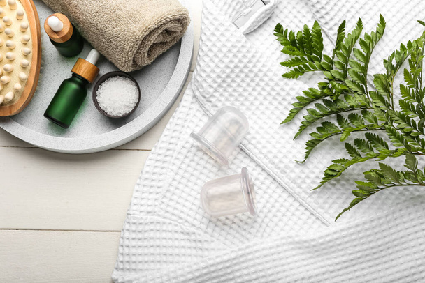 Vacuum jars for anti-cellulite massage, bathrobe and bath supplies on white wooden background - Fotografie, Obrázek