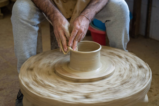 Potter shaping a piece of clay on a low wheel in Amarante, Portugal. - Φωτογραφία, εικόνα