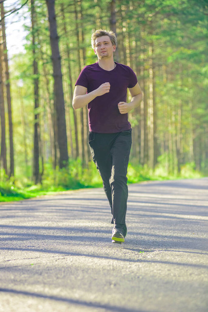 Man jogging in city partk at beautiful summer day. Sport fitness model caucasian ethnicity training outdoor. - Foto, imagen