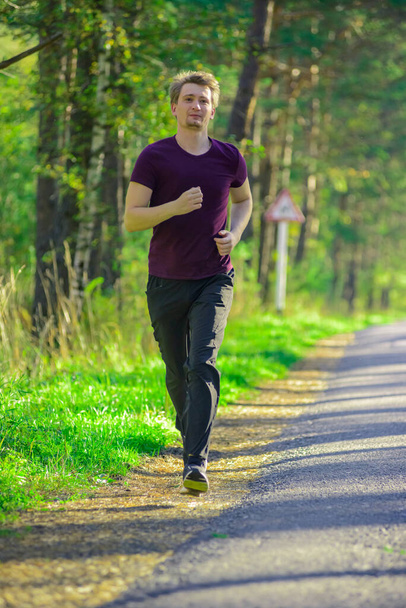 Man jogging in city partk at beautiful summer day. Sport fitness model caucasian ethnicity training outdoor. - Foto, afbeelding