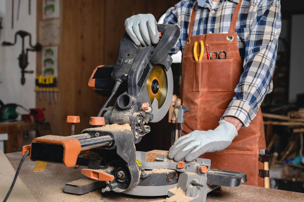 Carpinteiro usando uma serra circular elétrica, cortando o pedaço de madeira. - Foto, Imagem