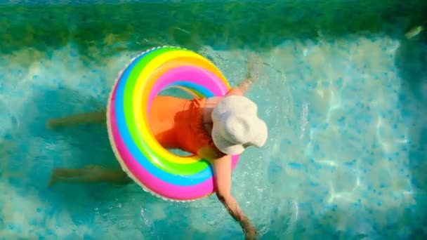 Chica con un anillo inflable arco iris en la piscina.Tiempo de verano - Metraje, vídeo