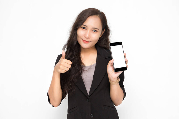 Kaunis aasialainen liike nainen yllään musta puku käsi pitämällä älypuhelin ja peukalot esittää jotain valkoisella taustalla ja kopioi tilaa. Itsevarma aasialainen työskentelevät nainen hymyilee ja iloinen - Valokuva, kuva