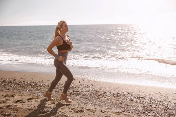 Boldog fiatal nő fut végig gyönyörű tengerparton - Fotó, kép