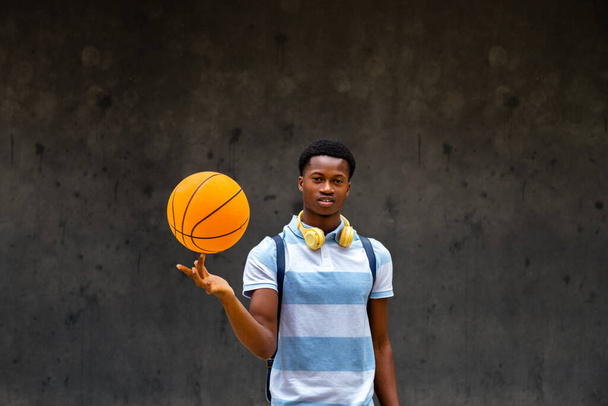 Teen African American boy spinning basketball ball on finger looking at camera. Copy space. - Фото, зображення