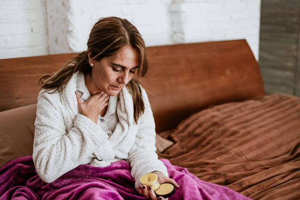 latin chory senior dojrzała kobieta kichanie i za pomocą serwetki na grypę na łóżku w domu w Meksyku Ameryka Łacińska - Zdjęcie, obraz