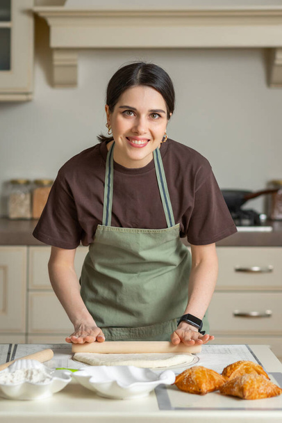 Aranyos fiatal barna mosolygós nő a konyhában kötény főzés házi sütés a konyhában - Fotó, kép
