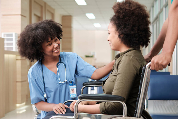 Young African American female doctor with stethoscope in uniform checks injury patient girl in wheelchair at outpatient accident clinic hospital, illness medical clinic examination, healthcare hall. - Fotoğraf, Görsel
