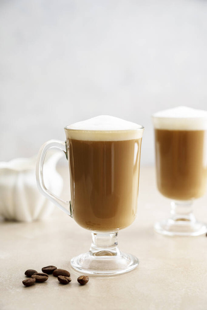 Coffee in glass ?ups with whipped milk foam on neutral background. Copy space - Foto, afbeelding