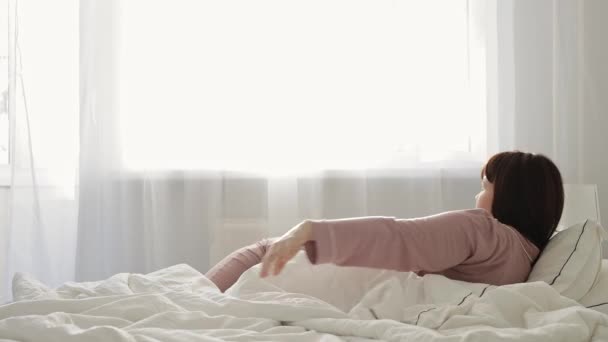 buongiorno concetto - giovane donna svegliarsi in camera da letto luminosa - Filmati, video