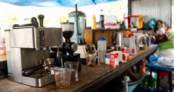 Disordered old small local dirty coffee shop wood bar counter interior design with espresso americano making machine, blender, grinder, sweeten condensed milk and other material ingredient equipment. - Foto, imagen