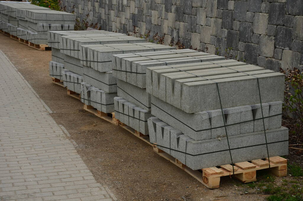 pallets with curbs ready for road and sidewalk reconstruction. Builders use cheap gray concrete products from a cement plant. separates the road and the sidewalk - Foto, Imagen