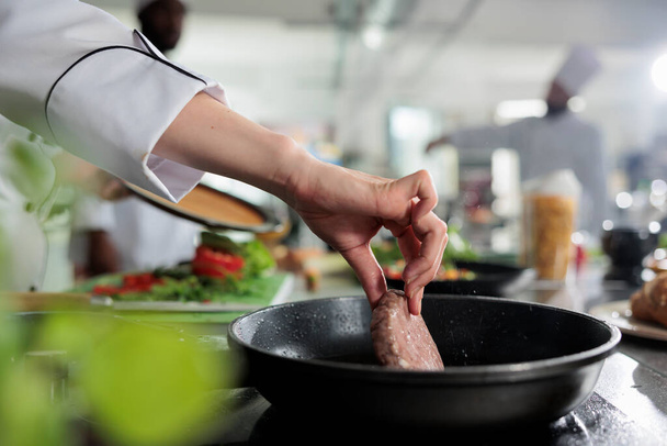Close up de mestre chef mãos cozinhar carne bovina em panela quente enquanto cozinha prato gourmet para o serviço de jantar. - Foto, Imagem