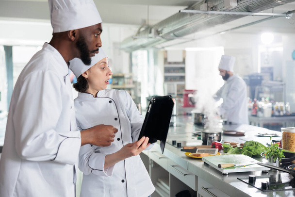 Esperti di cucina gourmet con tablet moderno alla ricerca di idee per piatti di servizio cena su internet. - Foto, immagini