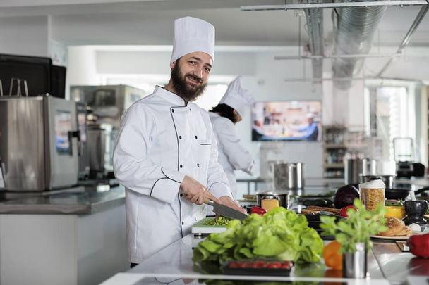 Gastronomy expert cooking delicious organic food using fresh ingredients while smiling confident at camera. - Fotó, kép