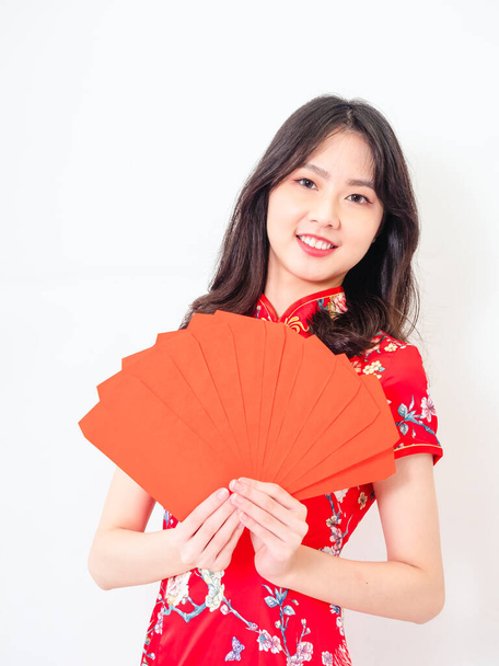 Portrait of Young asian woman wearing traditional cheongsam qipao dress with red envelopes in chinese new year on white background. - Foto, imagen