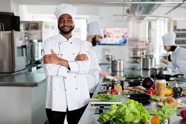 Gastronomie expert staande in restaurant professionele keuken met armen gekruist terwijl glimlachen op de camera. - Foto, afbeelding