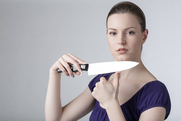 A young woman is playing with a sharp kitchen knife  - Foto, immagini