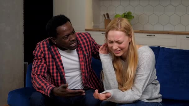 African American man comforting upset woman sitting on couch at home kitchen - Footage, Video