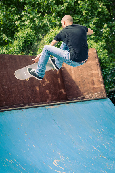 Skateboarder jumping in halfpipe at skatepark. - Fotoğraf, Görsel