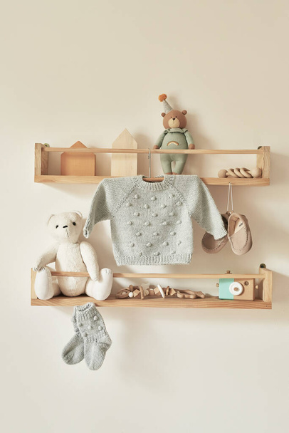 Children's knitted clothes on hanger. Jacket, jumper, hat, shoes. toys. Children's room, nursery. - Fotografie, Obrázek