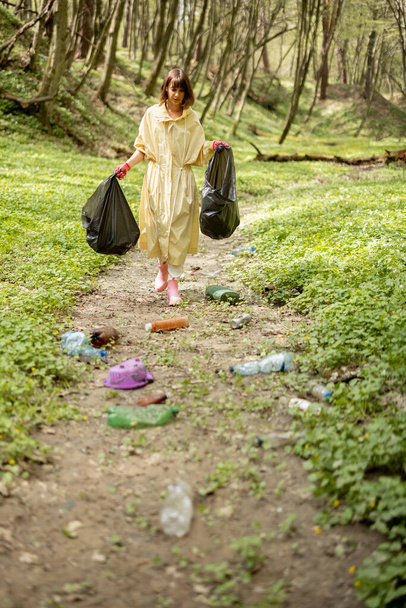 Жінка збирає розкидані пластикові сміття в лісі
 - Фото, зображення