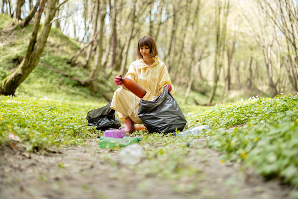 Γυναίκα συλλογή διάσπαρτα πλαστικά σκουπίδια στο δάσος - Φωτογραφία, εικόνα