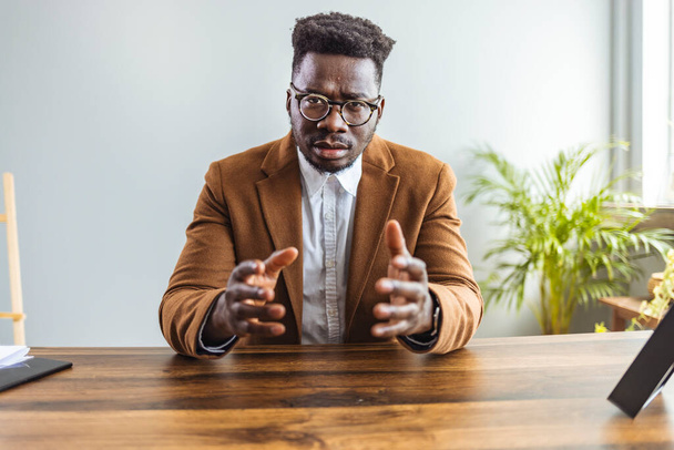 young african american businessman in glasses looking at camera and gesturing - Foto, afbeelding