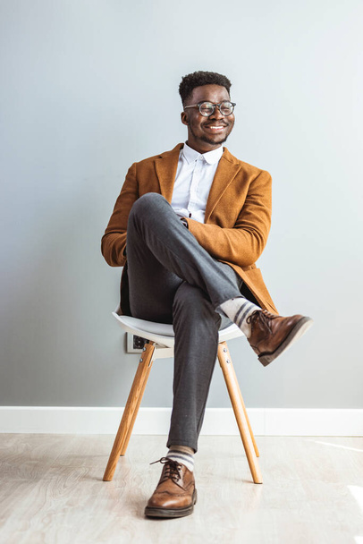 african american man sitting on chair in studio - Foto, Bild