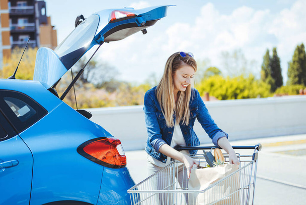 young woman loading groceries in car - Foto, Imagen