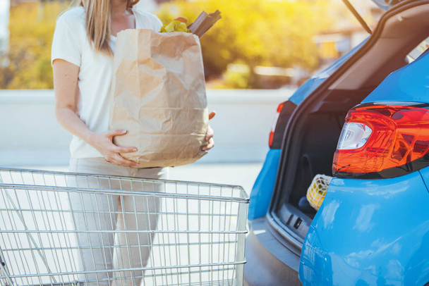 woman with paper shopping bag near car - Photo, Image