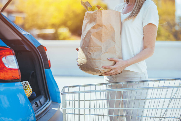 woman with paper shopping bag near car - Zdjęcie, obraz