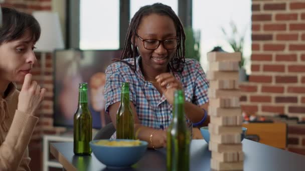 Uomini e donne che giocano con pezzi di torre di legno sul tavolo - Filmati, video