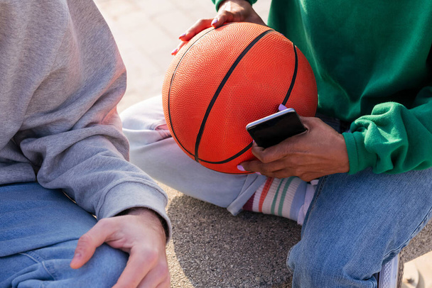 detail of a woman's hands holding a basketball and smart phone, concept of sport and modern lifestyle - Foto, imagen