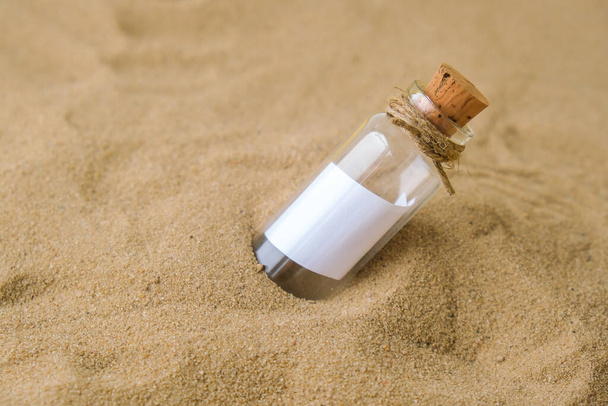 Flaschenpost am Strand. Insel-Lebensstil. Papierbotschaft in einer Glasflasche mit einem Korken im Sand. Hinweis zur Rettung, bitte helfen Sie. SOS-Konzept. Kopierraum. Mockup blank - Foto, Bild
