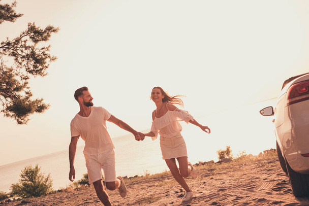 Full length body size photo young couple spending weekend near sea running holding hands - Foto, Imagem